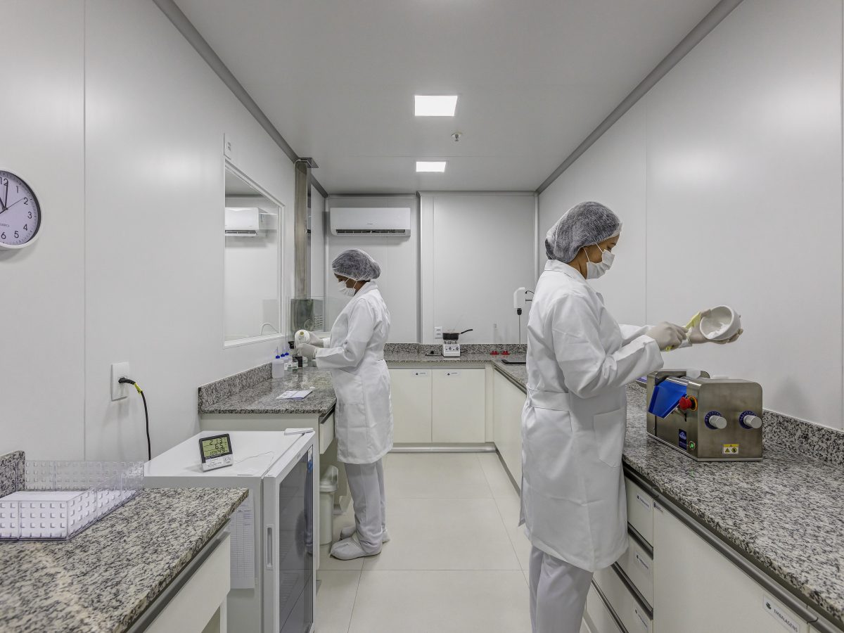 Duas farmacêuticas manipulando fórmulas em sala com bancadas de granito